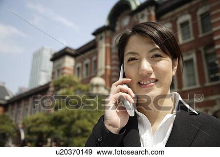 Portrait of a smiling young woman using mobile phone View Large Photo Image Stock Photo - Portrait of a smiling young woman using mobile phone. Fotosearch