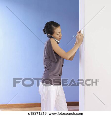 Side profile of a young woman talking on a mobile phone View Large Photo Image Stock Photograph - Side profile of a young woman talking on a mobile phone. Fotosearch