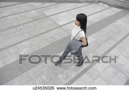 A side view of a woman walking on a broad pathway View Large Photo Image Stock Photograph - A side view of a woman walking on a broad pathway. Fotosearch