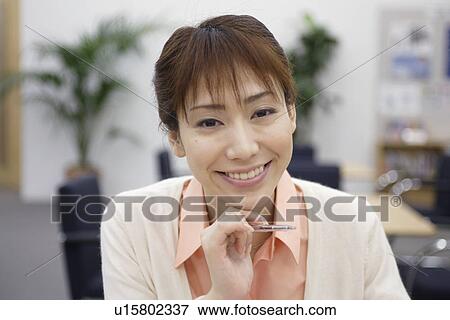 A woman holding a pen smiles at the camera View Large Photo Image Stock Photo - A woman holding a pen smiles at the camera. Fotosearch