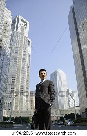 Stock Photograph - Businessman amid office buildings. Fotosearch