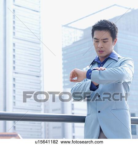 Low angle view of a businessman checking the time View Large Photo Image Stock Image - Low angle view of a businessman checking the time. Fotosearch