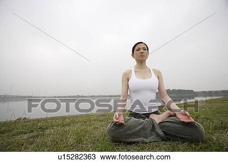 Stock Image - Front view of a woman in lotus position. Fotosearch