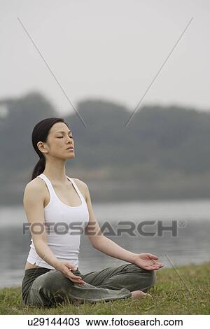 Stock Image - Front view of a woman in lotus position. Fotosearch