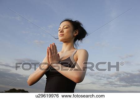 Stock Photograph - Low angle view of young woman performing yoga. Fotosearch