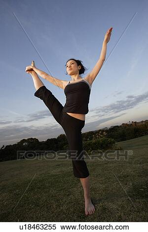 Stock Photography - View of a young woman balancing on one leg. Fotosearch