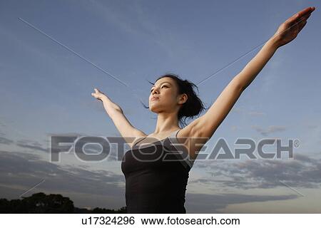 Stock Photograph - View of a young woman with hands raised. Fotosearch