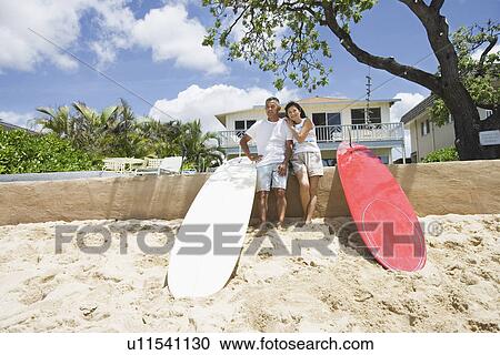A couple standing near surfboards View Large Photo Image Stock Image - A couple standing near surfboards. Fotosearch