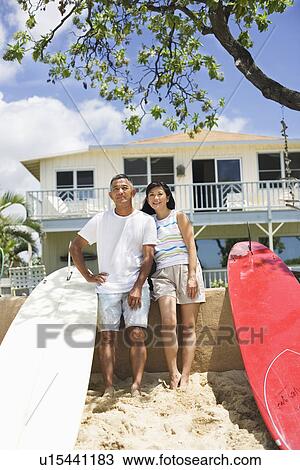 Stock Image - A couple standing near surfboards. Fotosearch