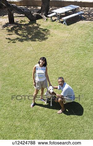 Stock Photo - A couple with dog in park. Fotosearch