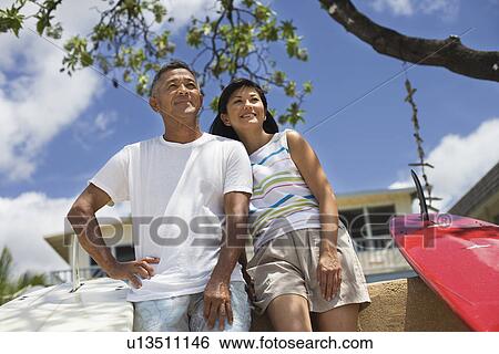 Low angle view of a couple looking away View Large Photo Image Stock Photograph - Low angle view of a couple looking away. Fotosearch