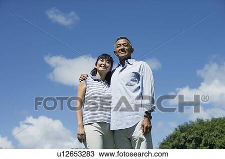 Low angle view of a couple standing together View Large Photo Image Stock Image - Low angle view of a couple standing together. Fotosearch