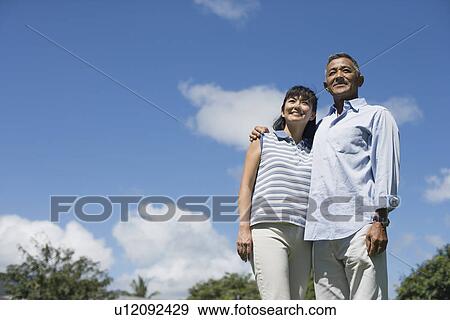 Low angle view of a couple standing together View Large Photo Image Stock Photo - Low angle view of a couple standing together. Fotosearch