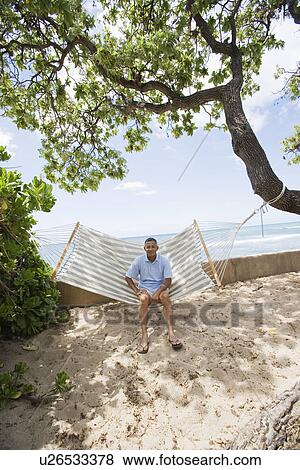 Stock Photo - Mature man sitting on hammock. Fotosearch