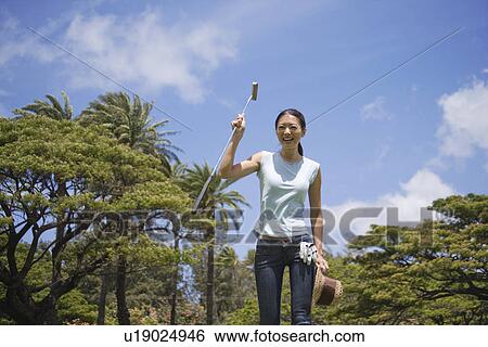 Stock Photograph - A woman holding golf club smiling. Fotosearch