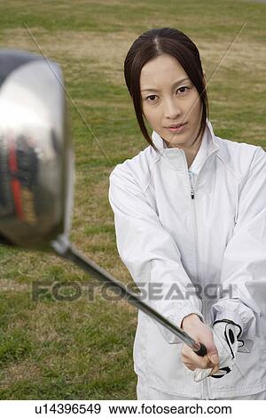 A young woman holding a golf club View Large Photo Image Stock Photo - A young woman holding a golf club. Fotosearch
