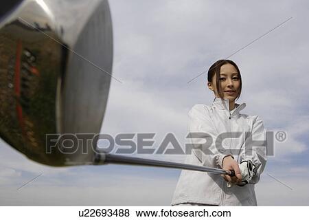 A young woman holding a golf club View Large Photo Image Stock Photo - A young woman holding a golf club. Fotosearch