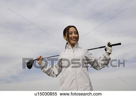 Stock Photography - A young woman holding a golf club. Fotosearch