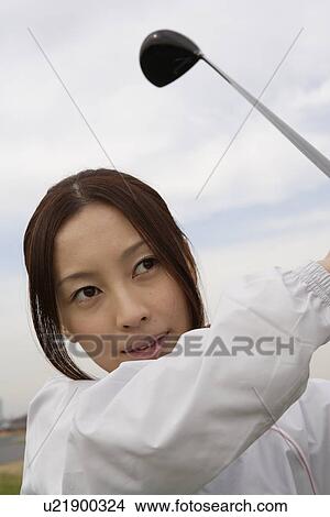 Picture - A young woman playing golf. Fotosearch