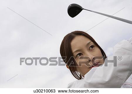 Stock Image - A young woman playing golf. Fotosearch