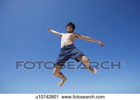 Low angle view of a young man jumping View Large Photo Image Stock Image - Low angle view of a young man jumping. Fotosearch