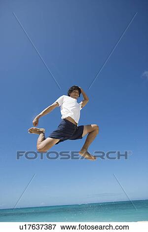 Stock Photo - Low angle view of a young man jumping. Fotosearch