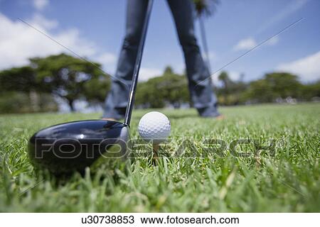 Stock Image - Person standing with golf club and ball. Fotosearch