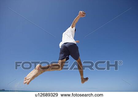 Rear view of a man jumping View Large Photo Image Stock Photo - Rear view of a man jumping. Fotosearch