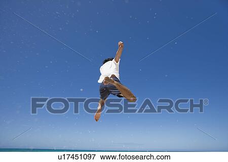Stock Photo - Rear view of a man jumping. Fotosearch