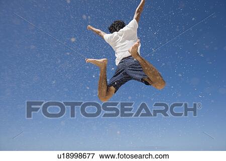 Stock Photo - Rear view of man jumping. Fotosearch