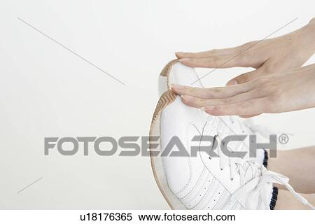 Stock Photography - Side view of white sport shoes being touched by a female. Fotosearch