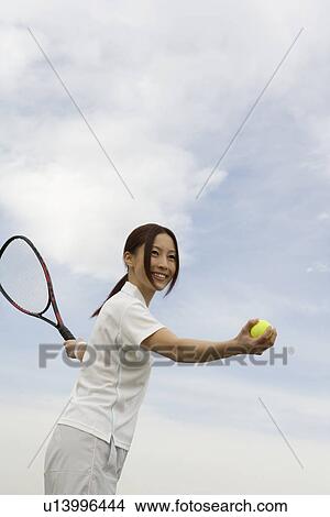 Young woman holding a tennis ball and a racquet View Large Photo Image Picture - Young woman holding a tennis ball and a racquet. Fotosearch