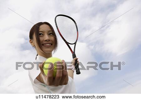 Young woman holding a tennis ball and a racquet View Large Photo Image Stock Image - Young woman holding a tennis ball and a racquet. Fotosearch