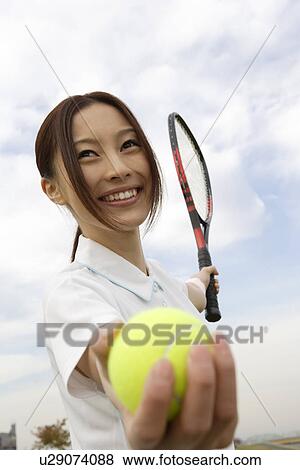 Young woman holding a tennis ball and a racquet View Large Photo Image Stock Photo - Young woman holding a tennis ball and a racquet. Fotosearch
