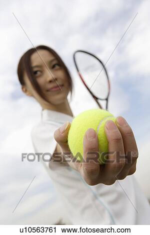 Stock Image - Young woman holding a tennis ball. Fotosearch