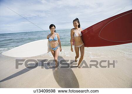 Young women walking with surfboards at beach View Large Photo Image Stock Photo - Young women walking with surfboards at beach. Fotosearch