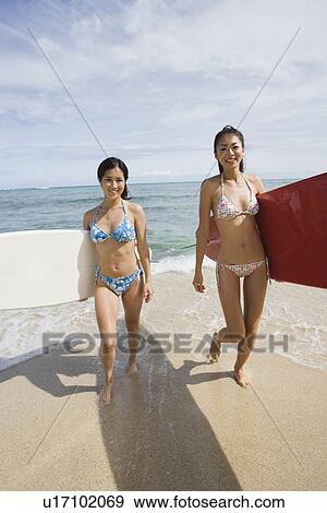 Young women walking with surfboards at beach View Large Photo Image Stock Photo - Young women walking with surfboards at beach. Fotosearch