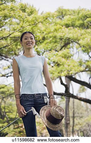 A woman holding golf club and hat View Large Photo Image Stock Image - A woman holding golf club and hat. Fotosearch