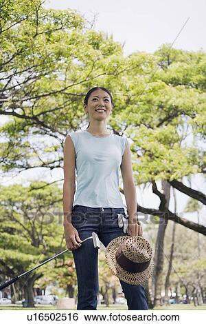 A woman standing with golf club and hat View Large Photo Image Stock Photograph - A woman standing with golf club and hat. Fotosearch