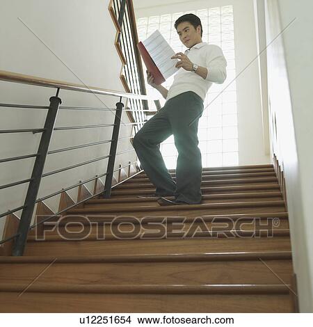 Picture - Low angle view of a businessman reading a file. Fotosearch