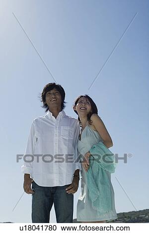 Stock Image - Low angle view of a young couple smiling. Fotosearch