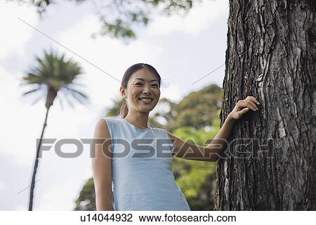 Low angle view of a young woman smiling View Large Photo Image Stock Image - Low angle view of a young woman smiling. Fotosearch