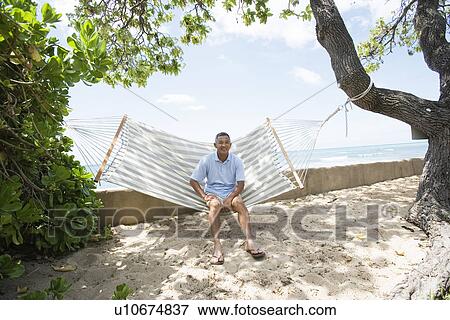 Stock Photo - Mature man sitting on hammock. Fotosearch