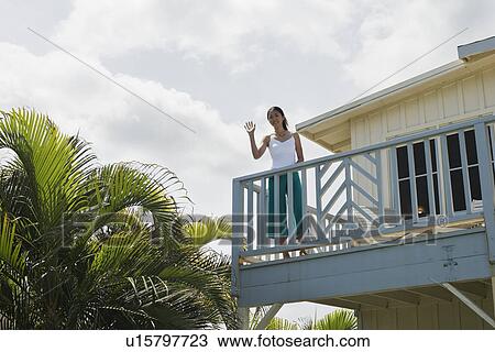 Portrait of a young woman waving from balcony View Large Photo Image Stock Image - Portrait of a young woman waving from balcony. Fotosearch