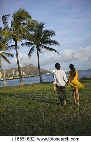 Rear view of a young couple walking View Large Photo Image Stock Image - Rear view of a young couple walking. Fotosearch