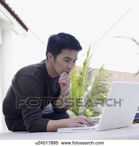 Stock Photography - Young man sitting on the floor using a laptop. Fotosearch