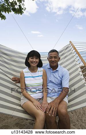 Stock Photo - A couple sitting on hammock. Fotosearch