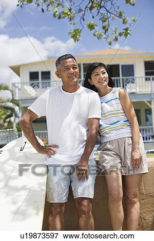 A couple standing near surfboard looking away View Large Photo Image Stock Photo - A couple standing near surfboard looking away. Fotosearch