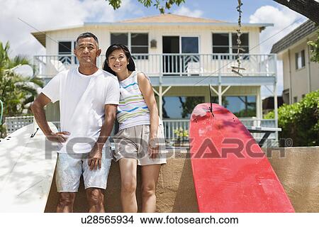 Picture - A couple standing near surfboards. Fotosearch