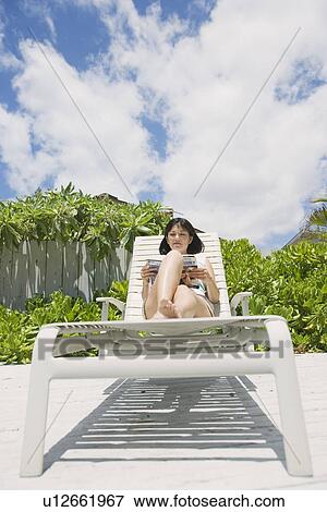 Stock Photo - A woman reading book on deckchair. Fotosearch